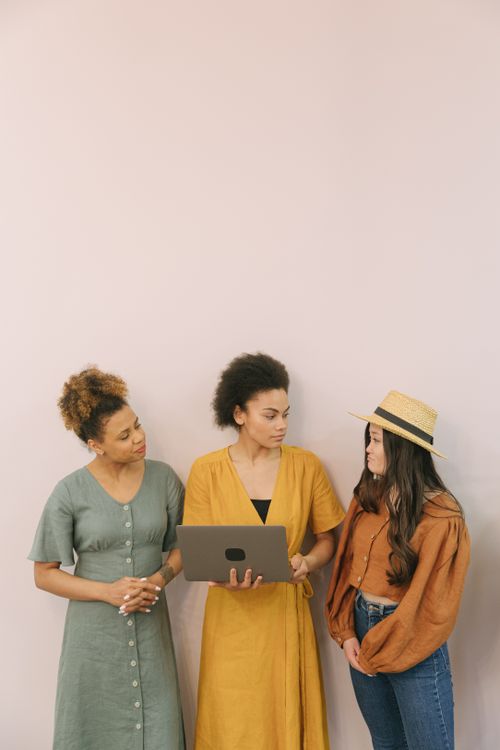 Free Three diverse women discussing plans in a modern office setting with a laptop. Stock Photo