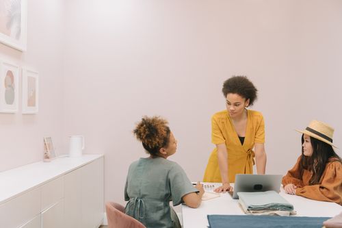 Free Three diverse women engaged in a collaborative meeting around a table in a stylish office. Stock Photo