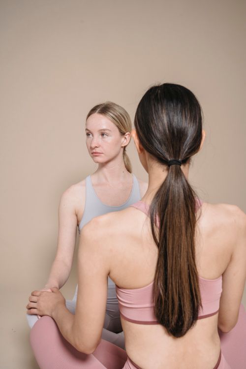 Free Two women in athletic attire engaged in a yoga session indoors, promoting fitness and relaxation. Stock Photo