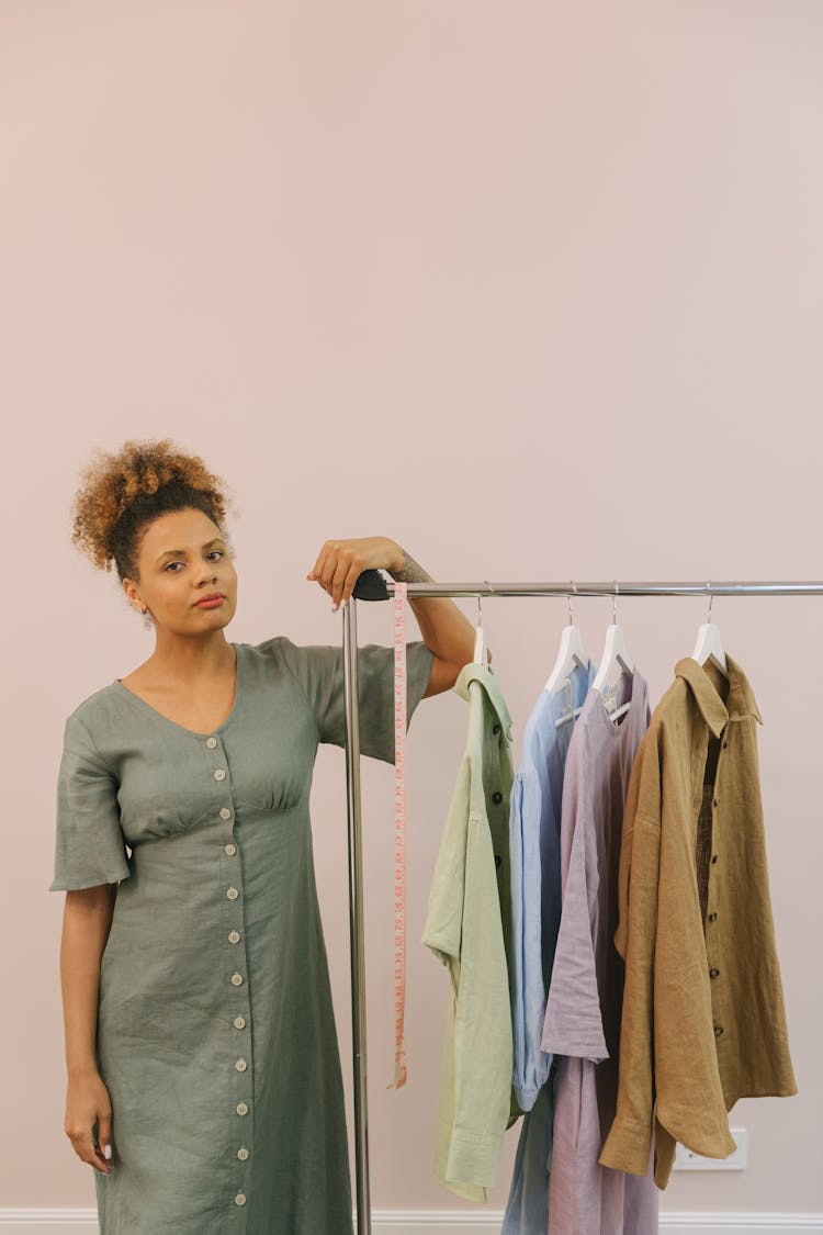 A Woman Holding On To A Clothes Rack With Hanged Clothes