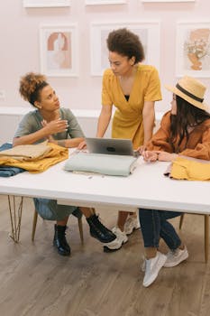 Group of diverse colleagues collaborating in a fashion-focused meeting with fabrics and laptop.