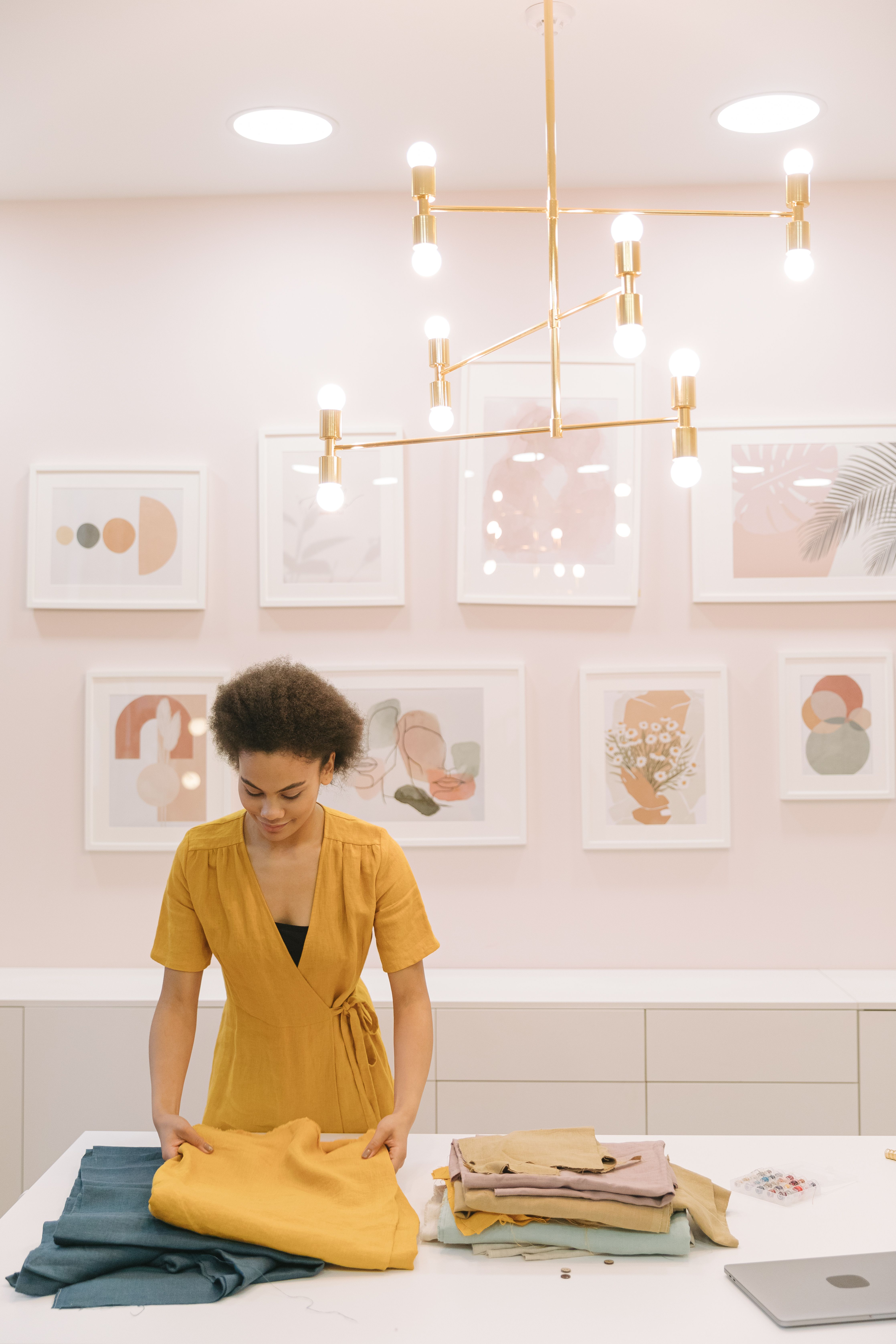 Woman in yellow dress organizing fabrics in a stylish boutique workplace.