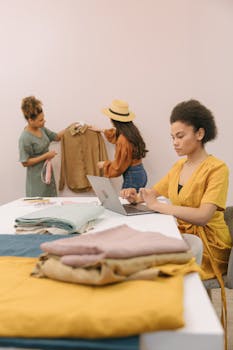 Team of diverse fashion designers working on new clothing line in a creative studio setting.