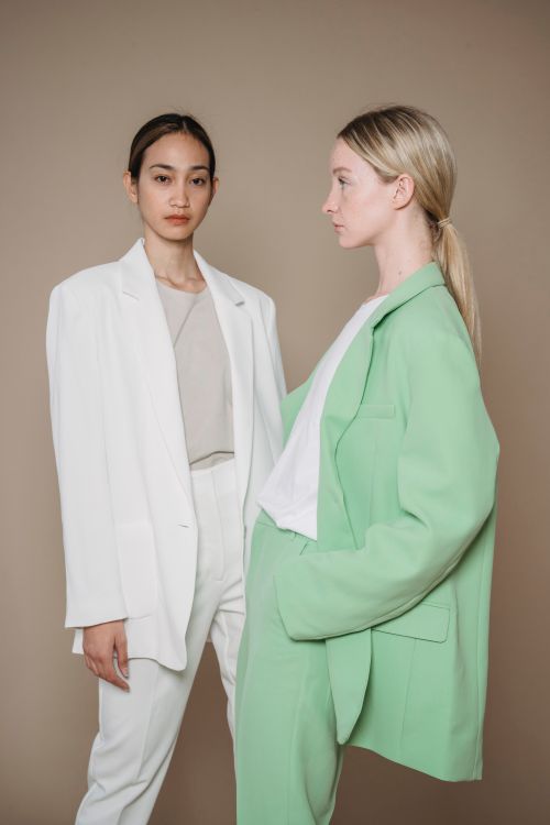Free Chic and stylish models posing in white and green suits against a neutral backdrop. Stock Photo