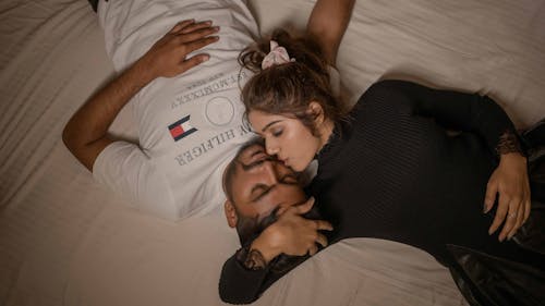 Free Woman Kissing Man Lying on Bed Stock Photo