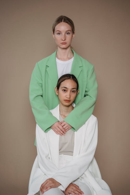 Woman in Green Blazer Embracing Woman in White Blazer