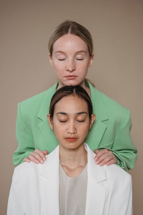 Free Stylish portrait of two women in blazers with closed eyes, conveying tranquility in a studio setting. Stock Photo