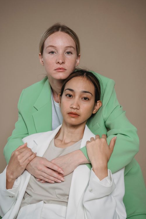 Free Modern studio portrait of two women wearing green and white blazers with serious expressions. Stock Photo