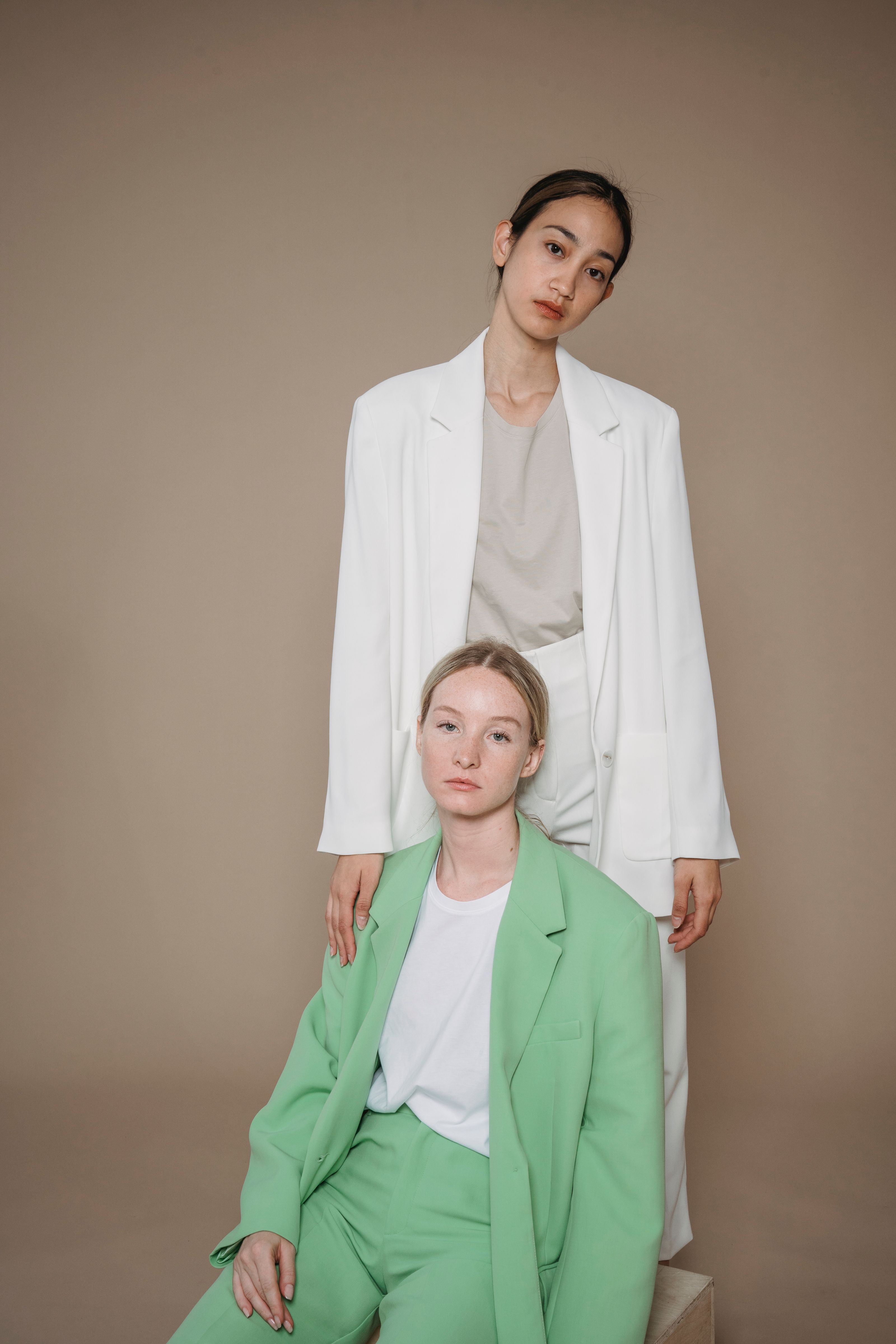 Mulheres estilosas posando em trajes complementares verde e branco. Ensaio no estúdio com estética moderna.