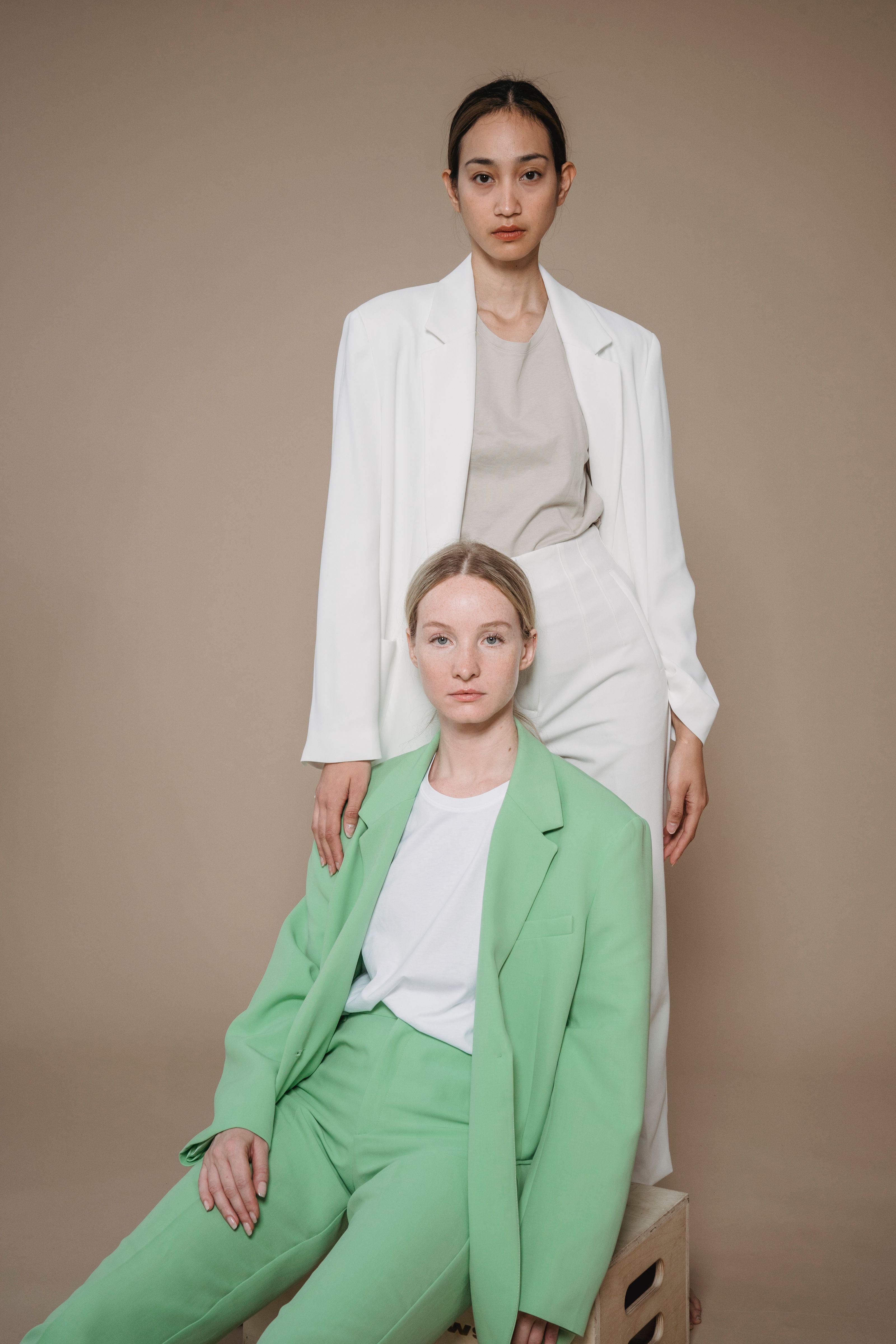Retrato de estúdio elegante de duas mulheres em blazers verde e branco. Estilo à frente da moda.