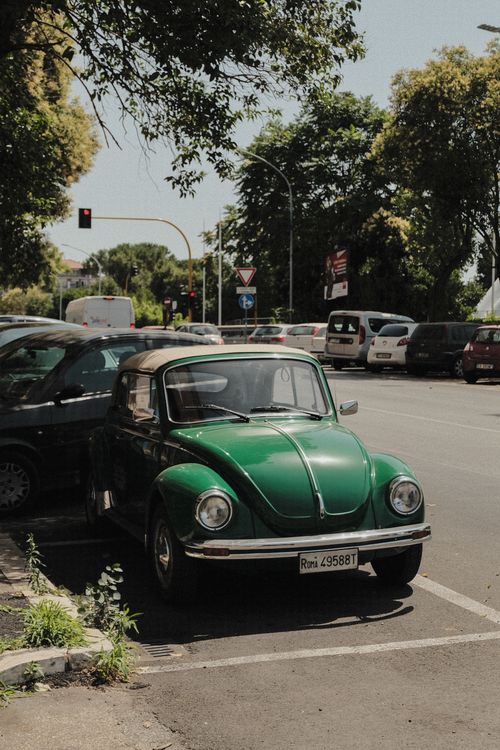 Free A classic green Volkswagen Beetle parked in an urban parking lot on a sunny day. Stock Photo