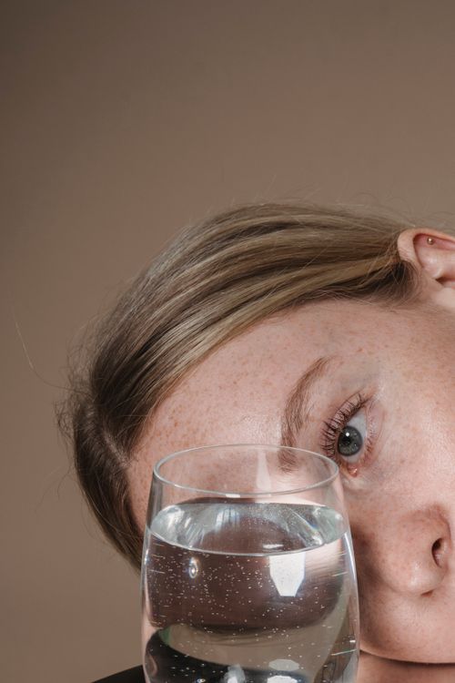 Free Intimate close-up of a woman gazing through a water glass, highlighting her features. Stock Photo