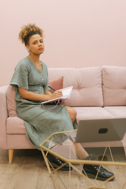 Free Woman Sitting on Sofa While Holding a Notebook Stock Photo
