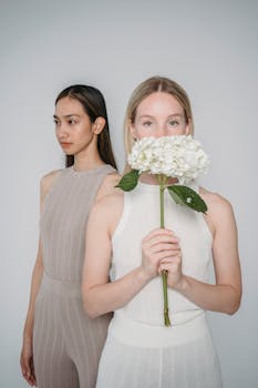 Stylish studio portrait of two women with modern fashion and floral accent.