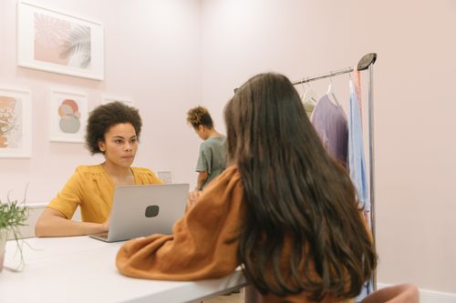 Free Two women in a stylish office setting working on a laptop and discussing projects. Stock Photo