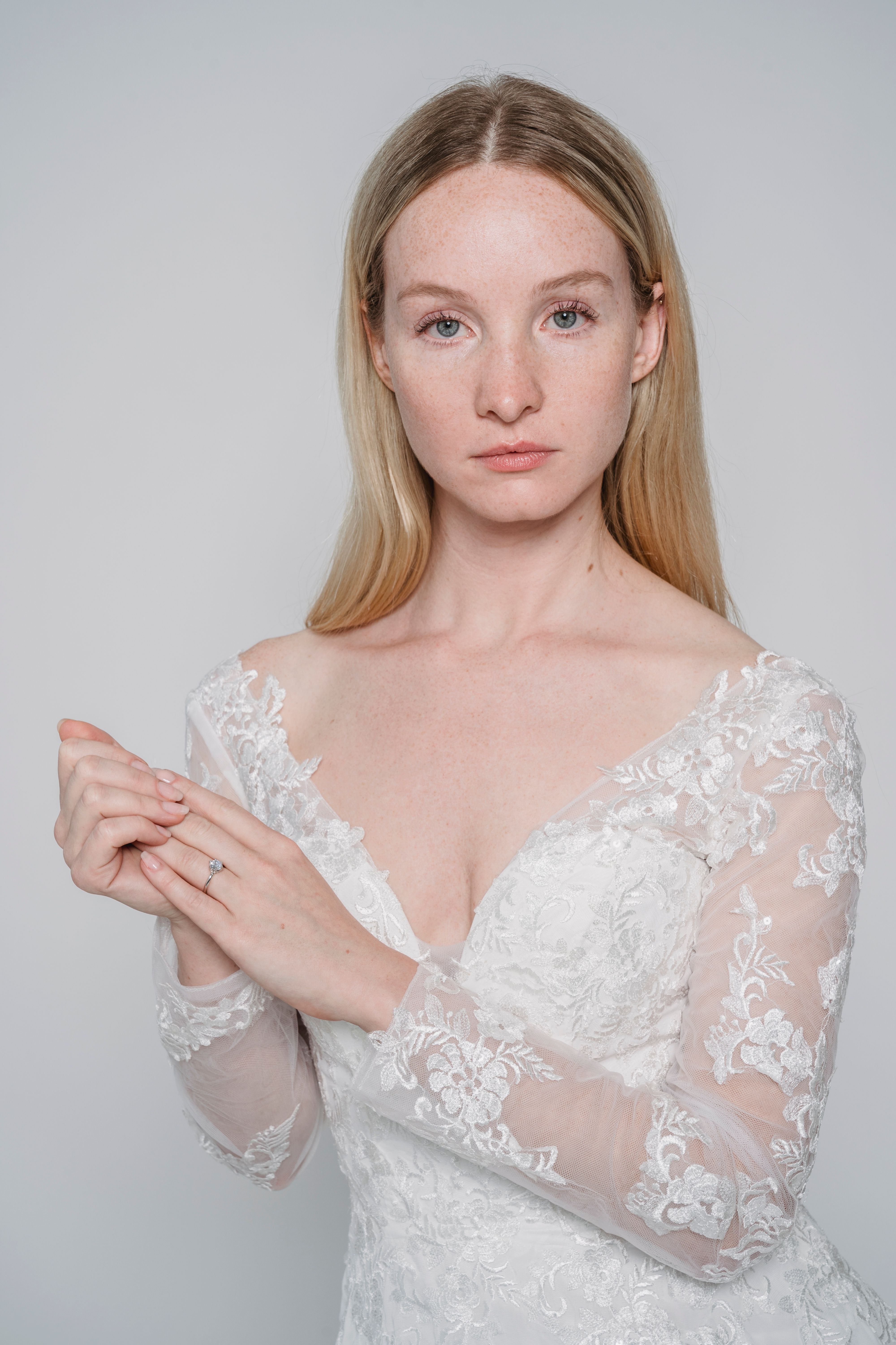 Elegant portrait of a bride in a lacy white dress. Captured in a studio, highlighting fashion and bridal themes.
