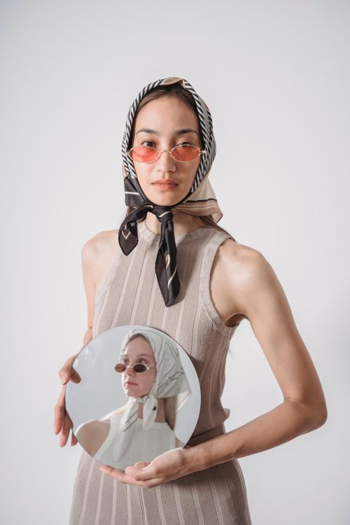 Free Fashionable woman in headscarf and sunglasses holding a mirror with reflection. Stock Photo