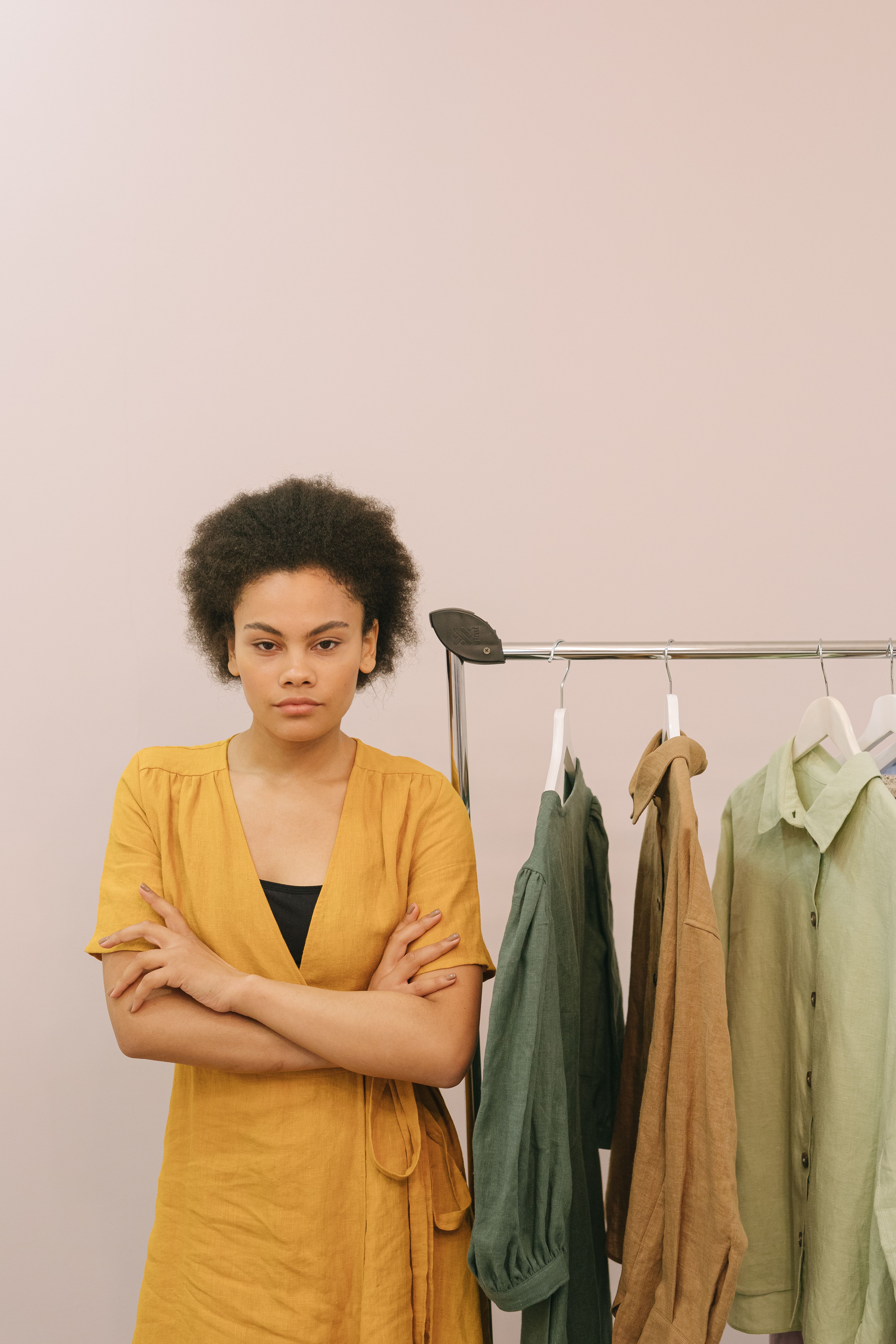 Woman in Yellow Dress Standing Beside a Clothing Rack · Free Stock Photo