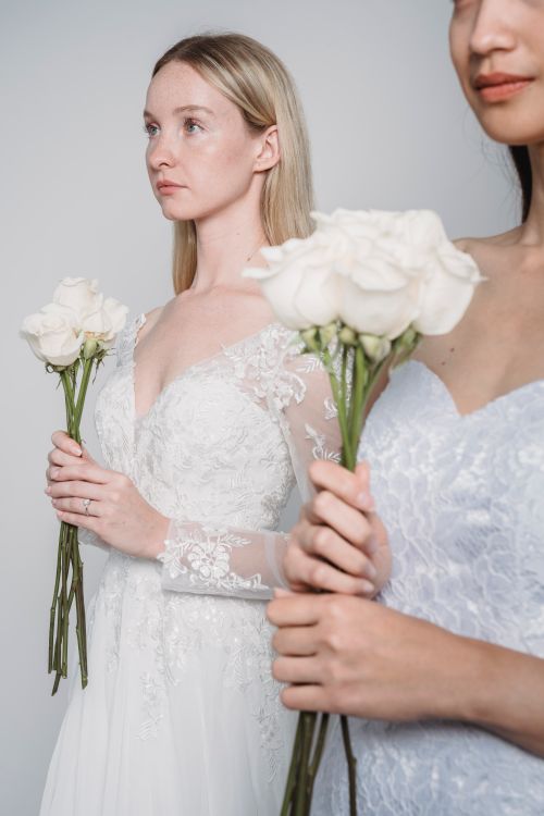 Free Two bridesmaids in lace dresses holding white roses at a wedding ceremony. Stock Photo