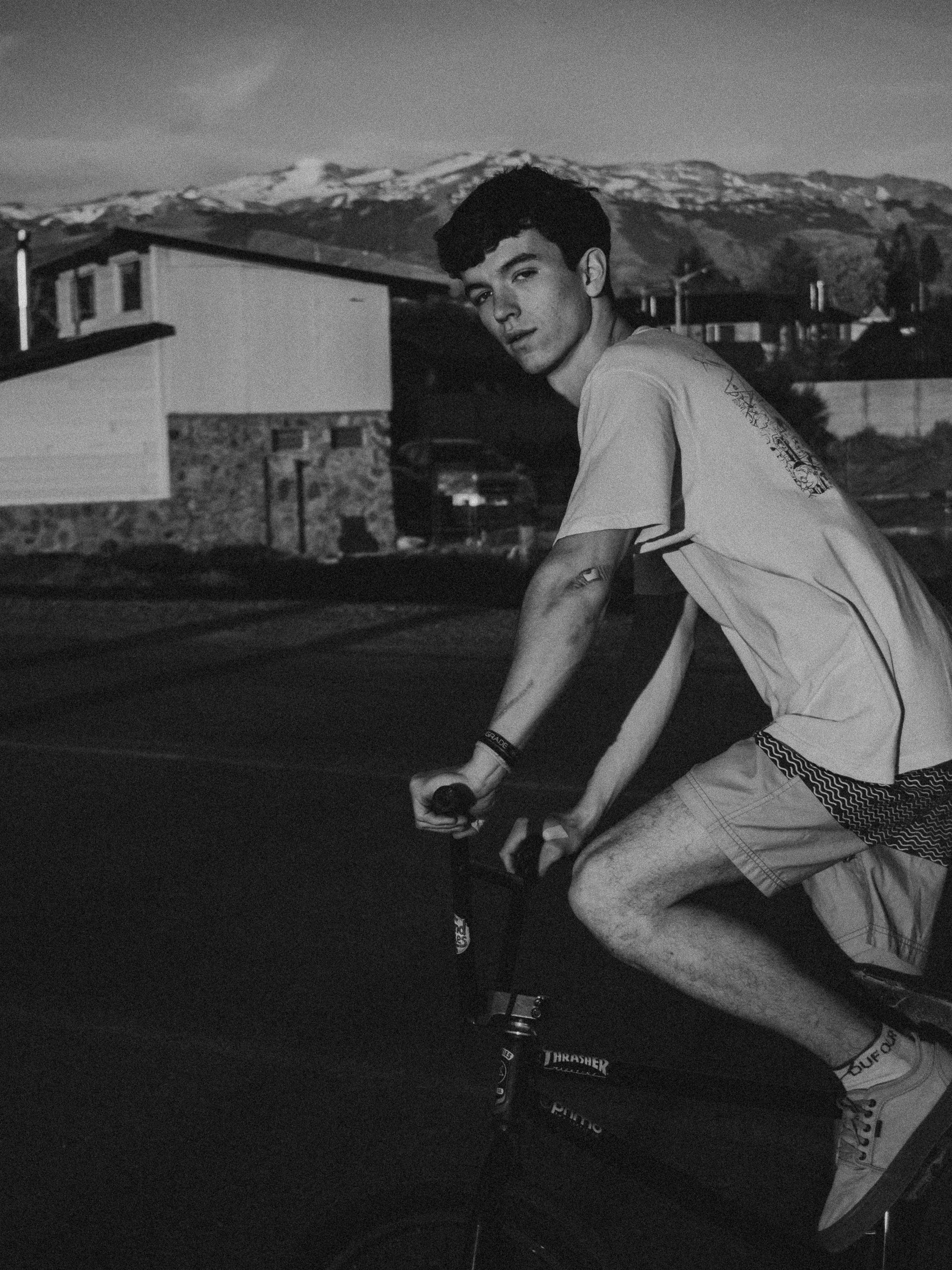 Monochrome image of a man riding a bicycle in a scenic mountain area.