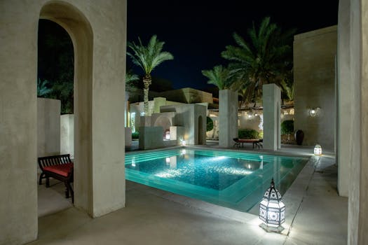 Elegant poolside setting at night with Dubai architecture and palm trees.