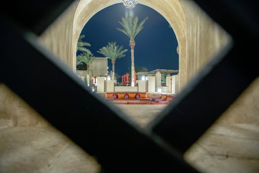 Illuminated view of luxury Arabian architecture and palm trees at night in Dubai, UAE.