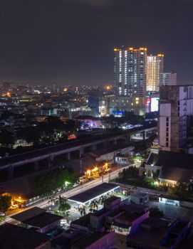 Aerial view of a bustling city at night featuring bright lights and high-rise buildings.