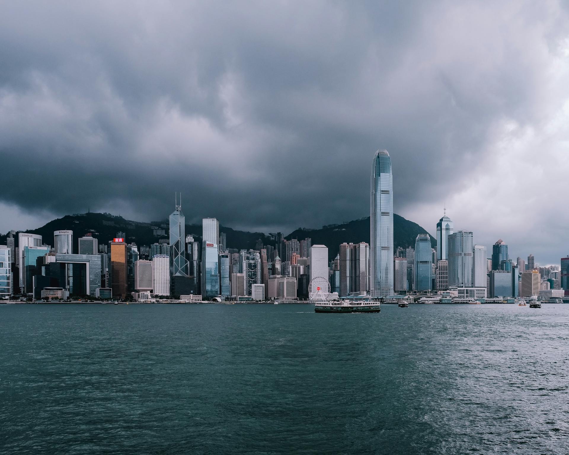 Hong Kong skyline with dramatic clouds over Victoria Harbour viewed from the waterfront.