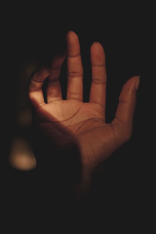 Free A close-up of an open hand against a dark background, highlighting expressive gestures. Stock Photo