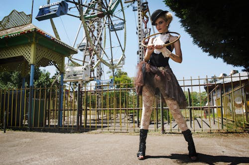 Woman in Black Camisole Top Stands Behind Ferris Wheel