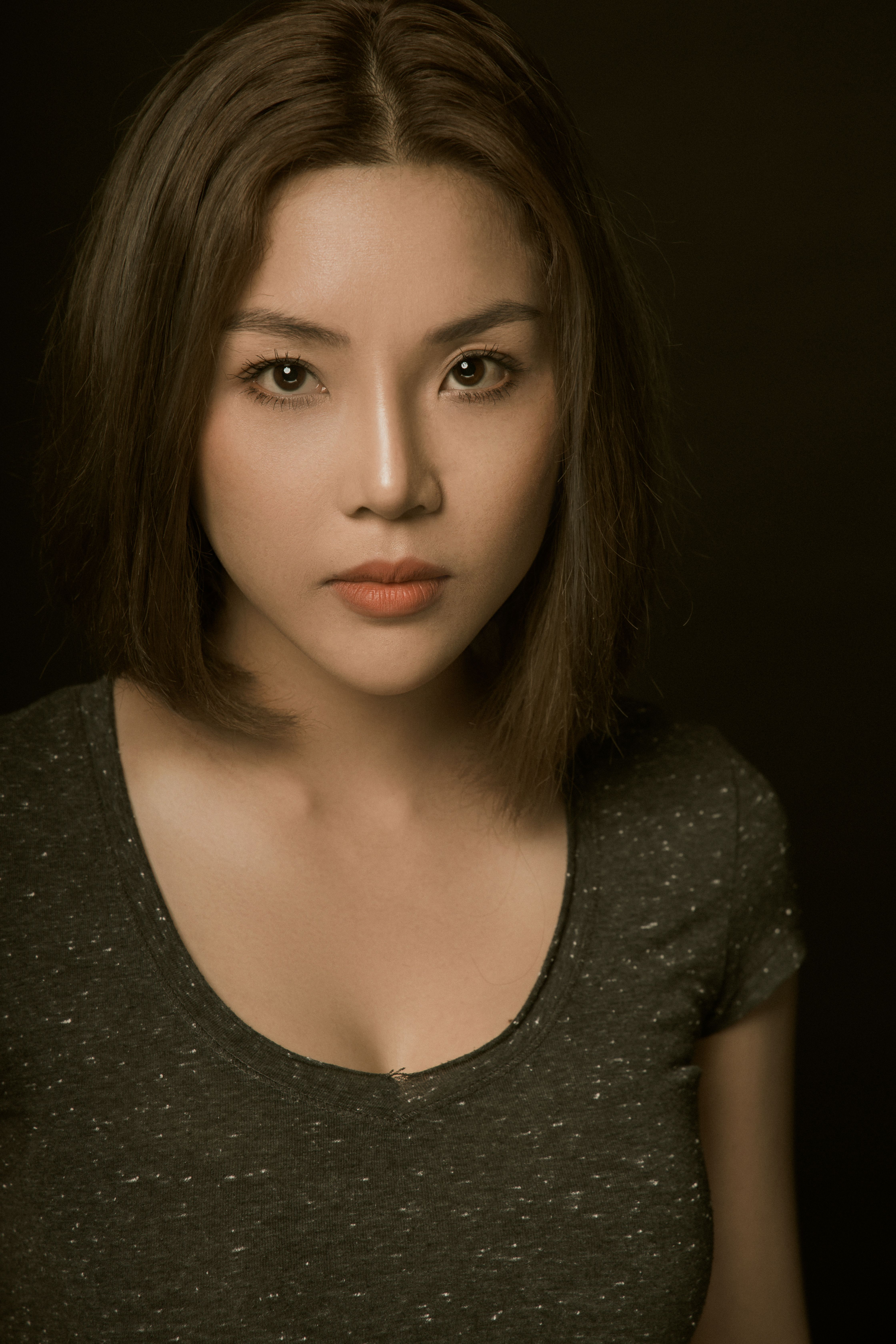 Close-up portrait of an adult woman with a neutral expression against a dark background.
