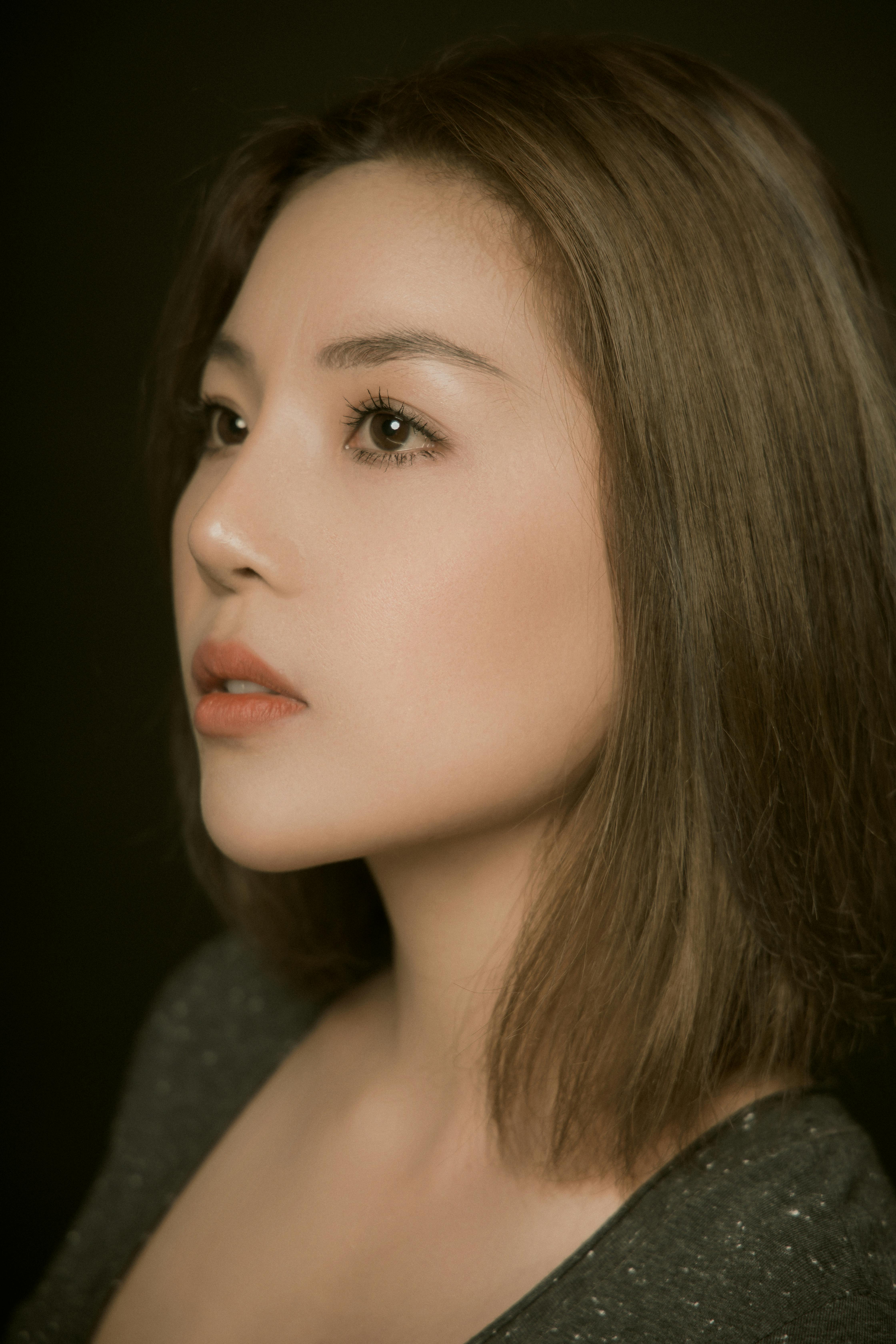 Close-up side profile portrait of an adult woman with serene expression, captured indoors.