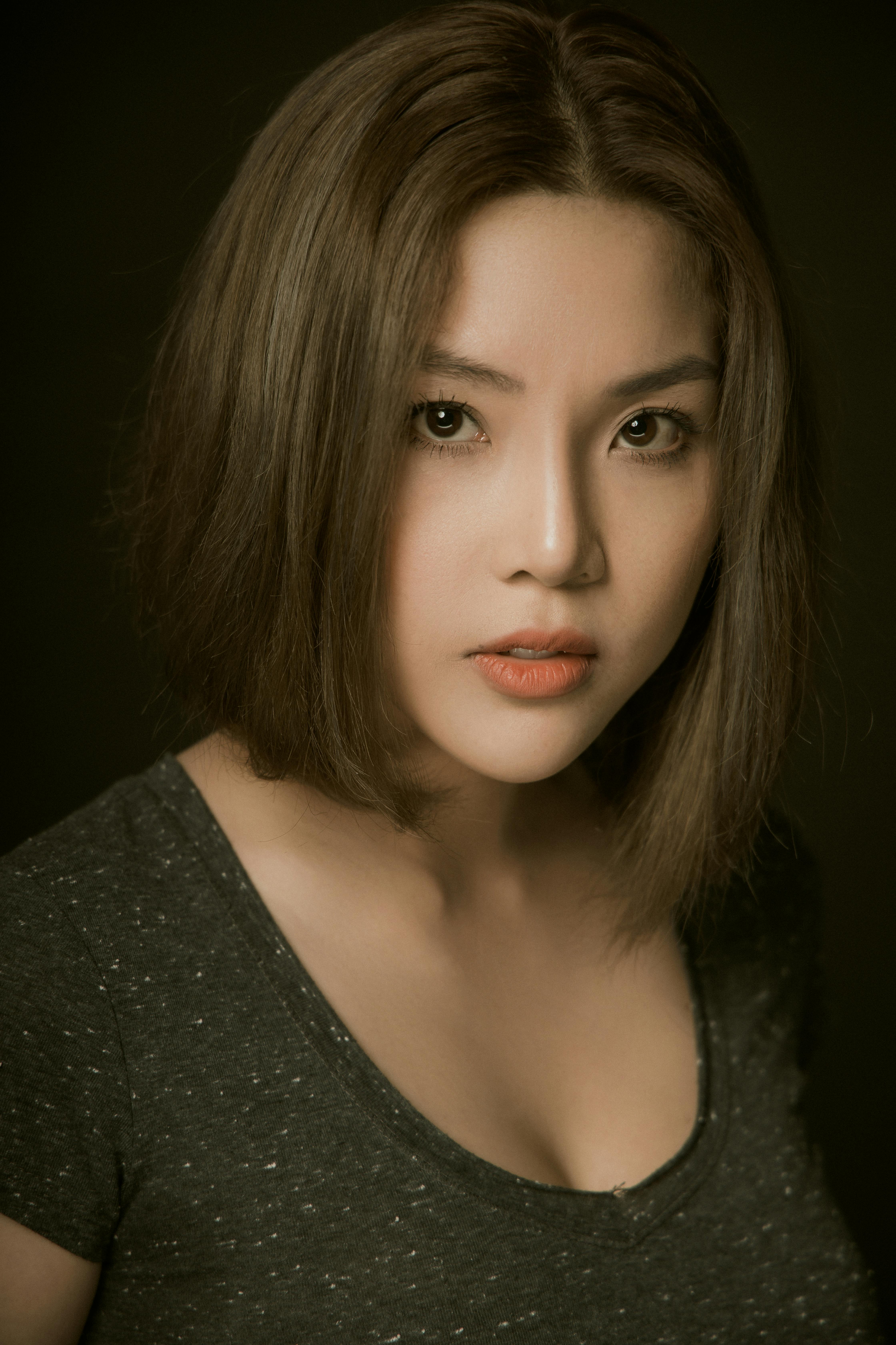 Close-up portrait of a woman with short hair and intense gaze, captured in a vertical shot.