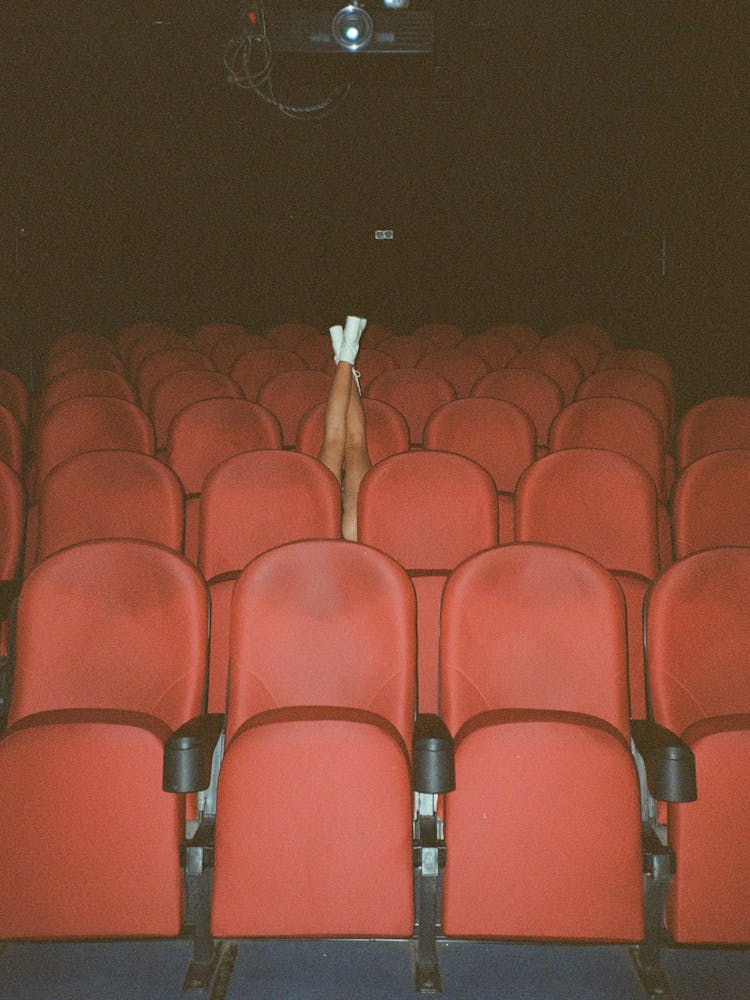 Person In White Shoes Sitting On Red Chairs