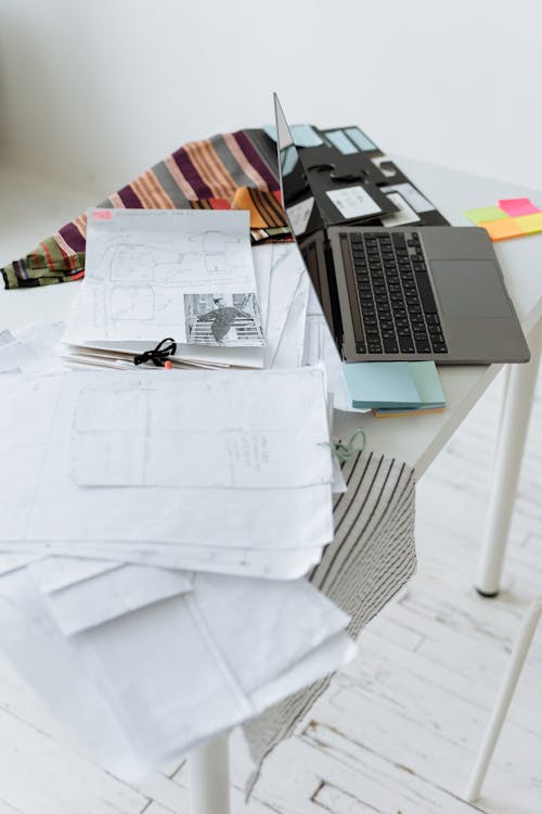 Free Laptop and Pile of Paper Documents on White Table Stock Photo