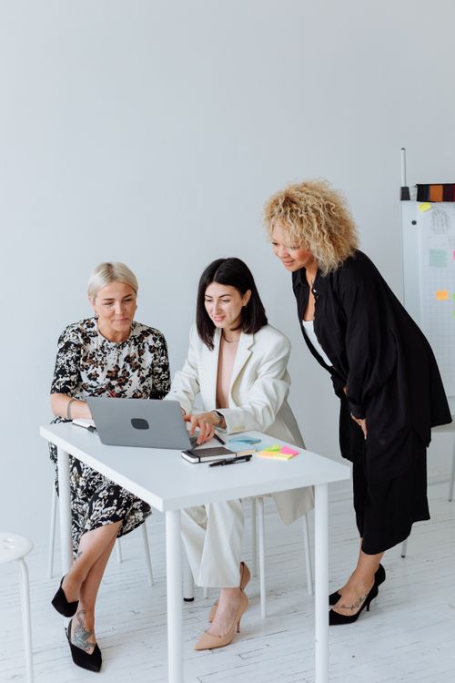 Free Three diverse women working together at a white table in an office setting. Stock Photo