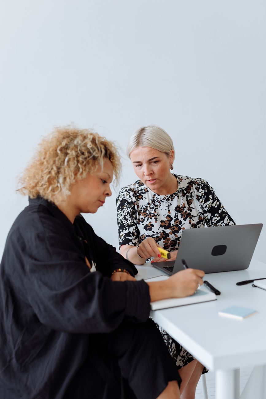 Two colleagues discussing a file, comparing a transaction coordinator vs a real estate assistant