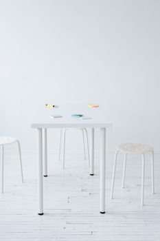 Elegant minimalist interior featuring a white table and stools on a wooden floor.