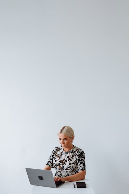Woman in Black and White Floral Shirt Using her Laptop