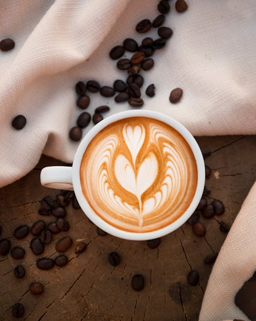 Free White Ceramic Mug With Coffee on Wooden Surface Beside the White Textile Stock Photo