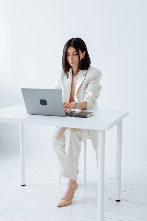 Beautiful Woman in White Blazer Using a Laptop
