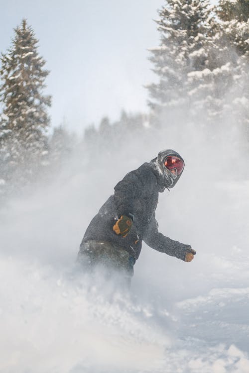 Person In Grauer Jacke Und Roter Schneebrille, Die Auf Snowboard Reitet