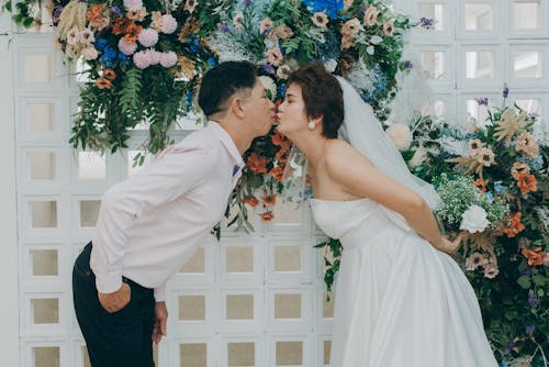 Man in White Suit Kissing Woman in White Dress