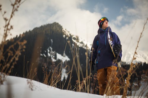 Lage Hoekfotografie Van Een Man Met Een Blauwe Jas Met Een Sneeuwbord