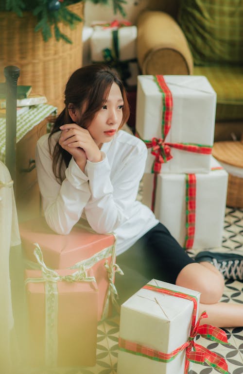 Woman in White Shirt Sitting Beside the Wrapped Boxes