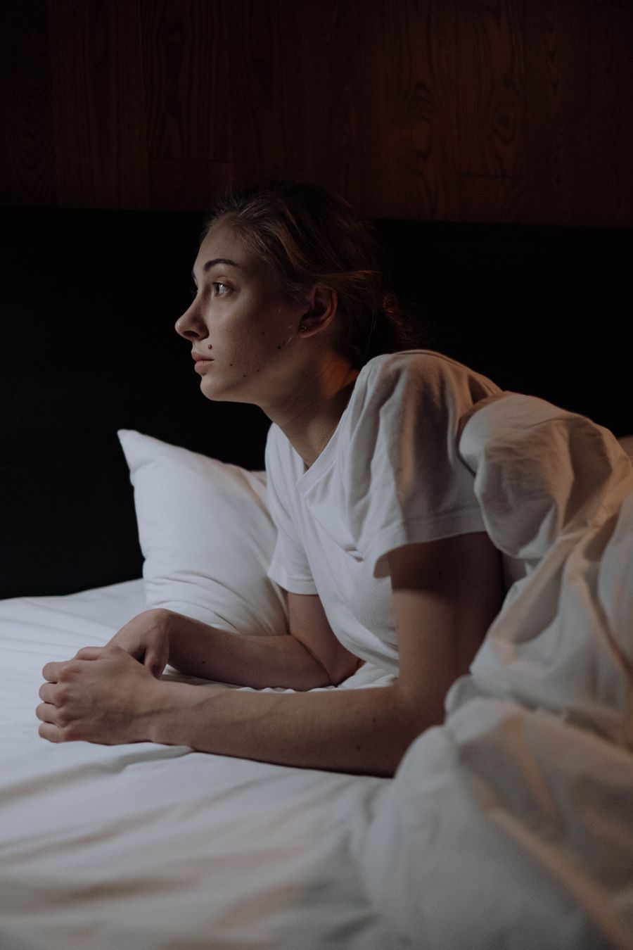 A woman lying awake in bed at night, propped on her arms, her mind still running.