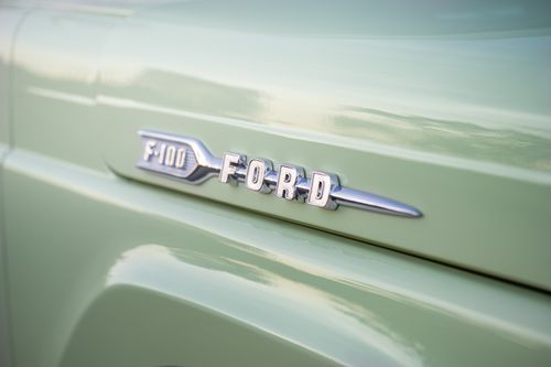 Free Close-up view of a vintage Ford F-100 emblem on a pastel green vehicle, ideal for automotive enthusiasts. Stock Photo