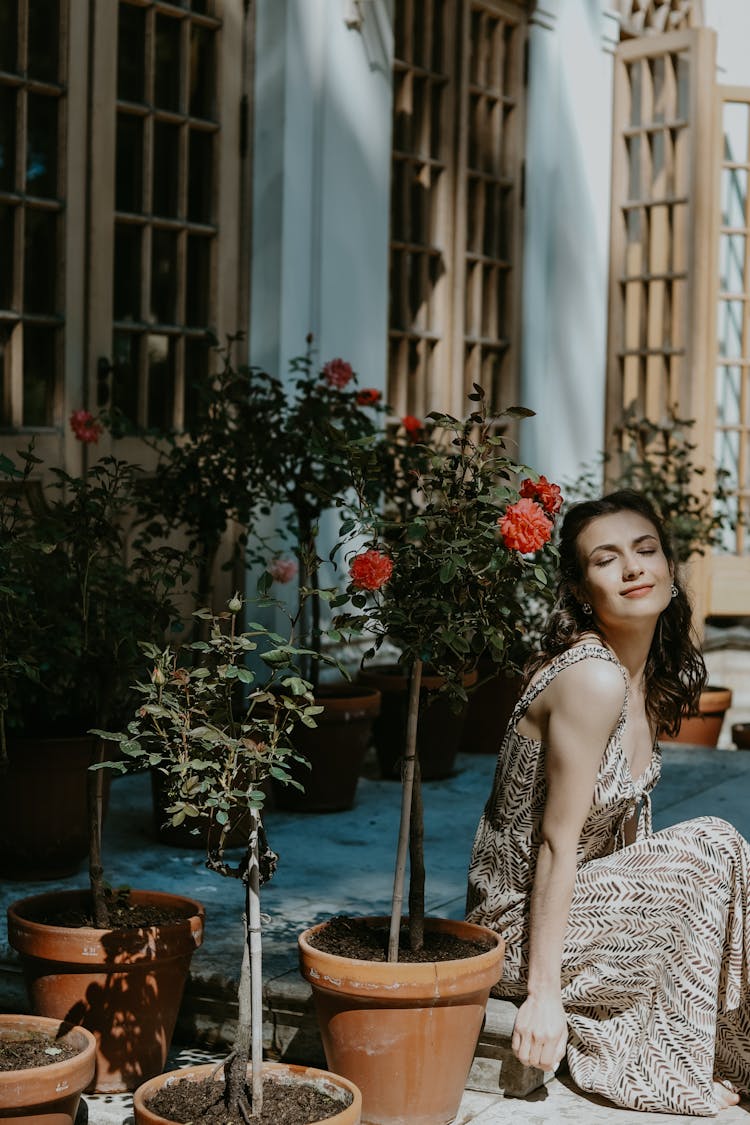 Woman Sitting By Blooming Potted Trees