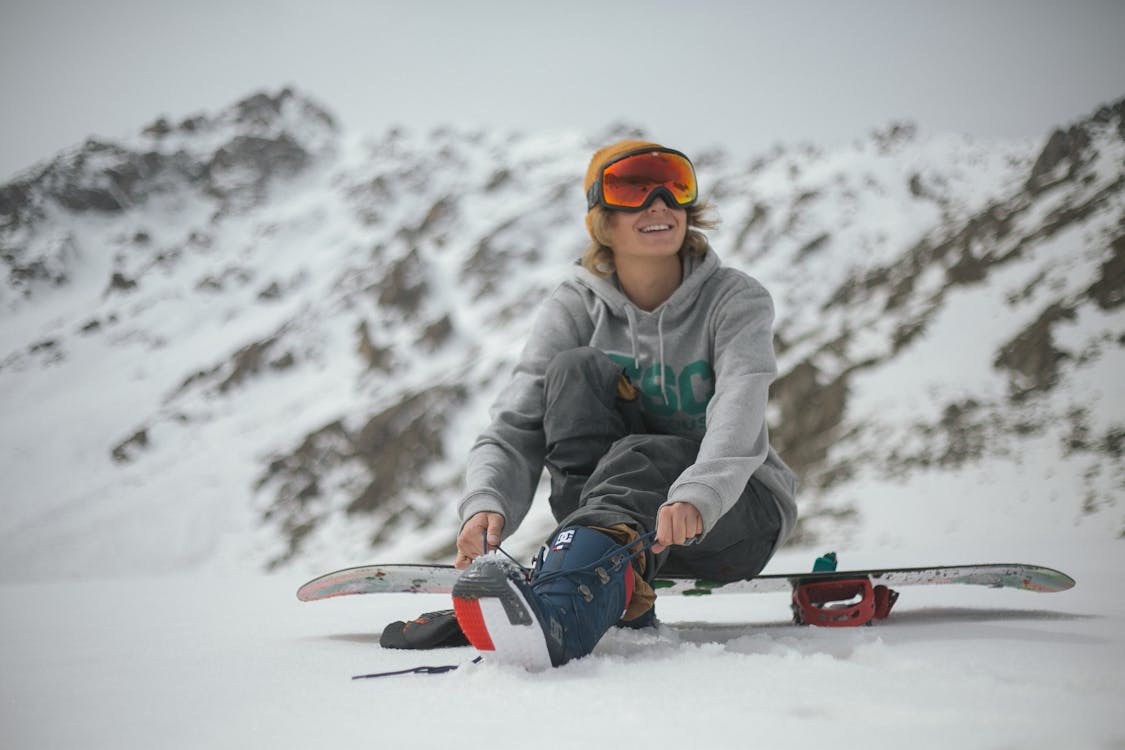 Free Person Im Grauen Hoodie, Der Auf Snowboard Sitzt Stock Photo