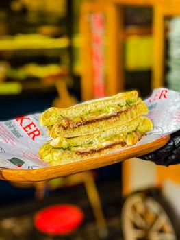 Close-up of a mouth-watering grilled cheese sandwich with lettuce on a wooden tray.